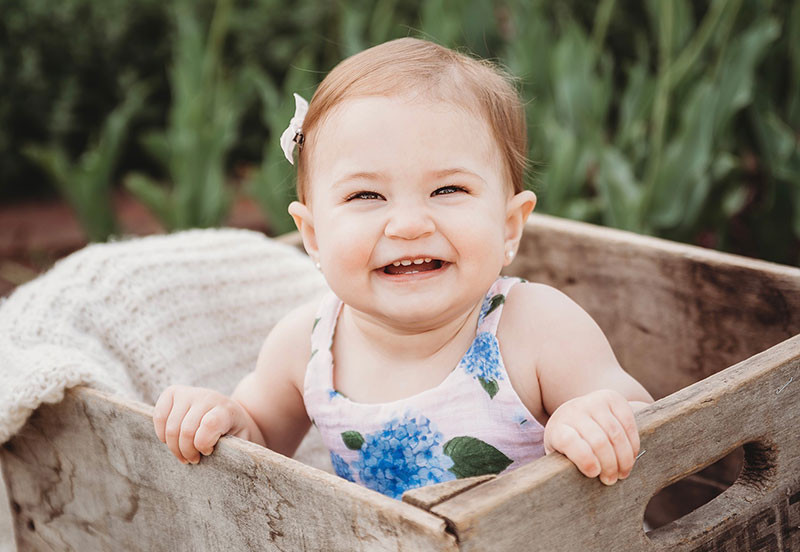 A smiling baby girl in a crate